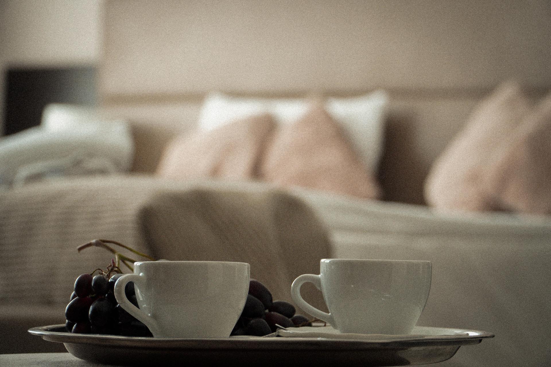 Two cups, in the background a hotel bed